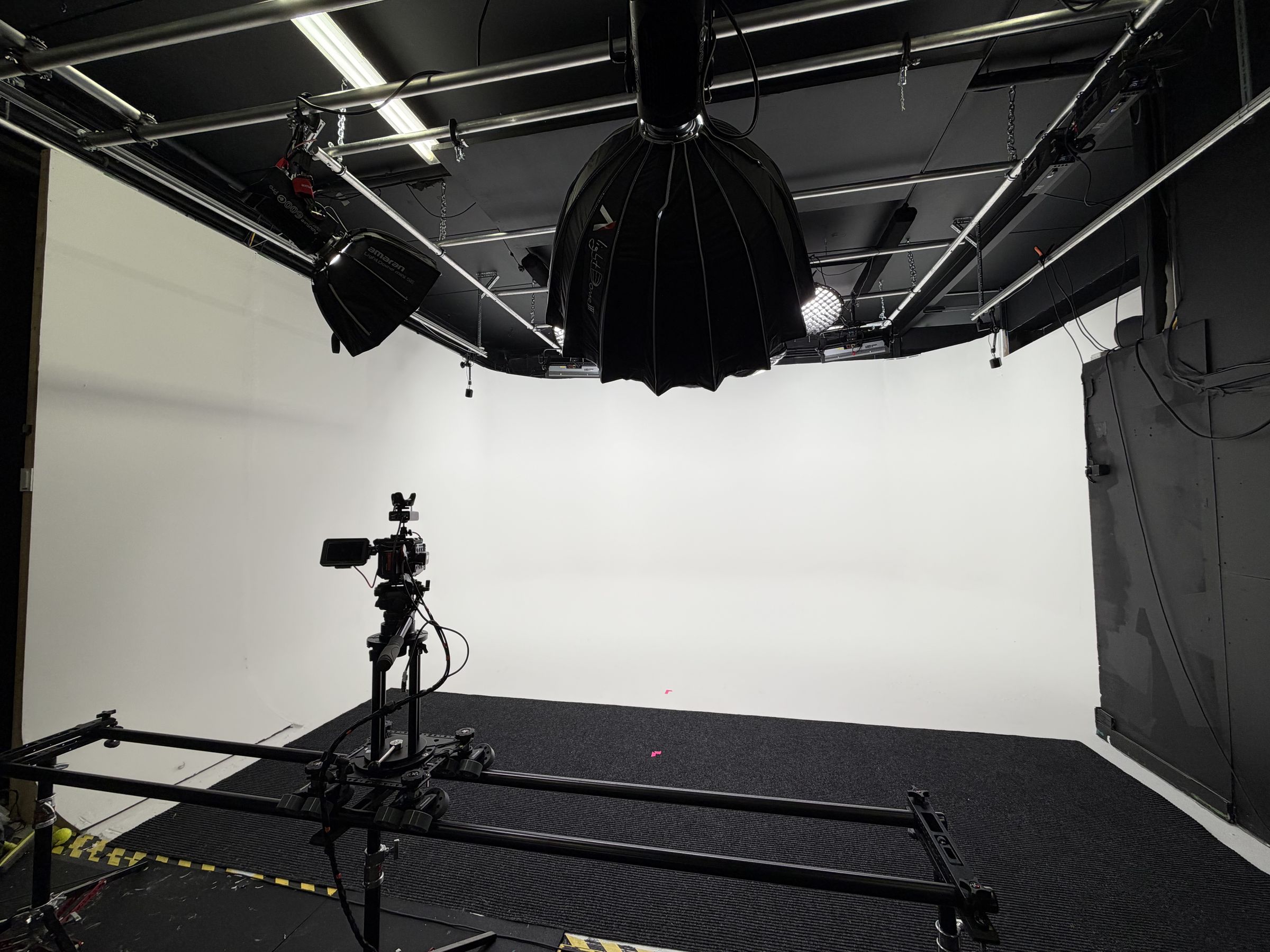 The white infinity studio with the lighting grid overhead and a camera on a slider